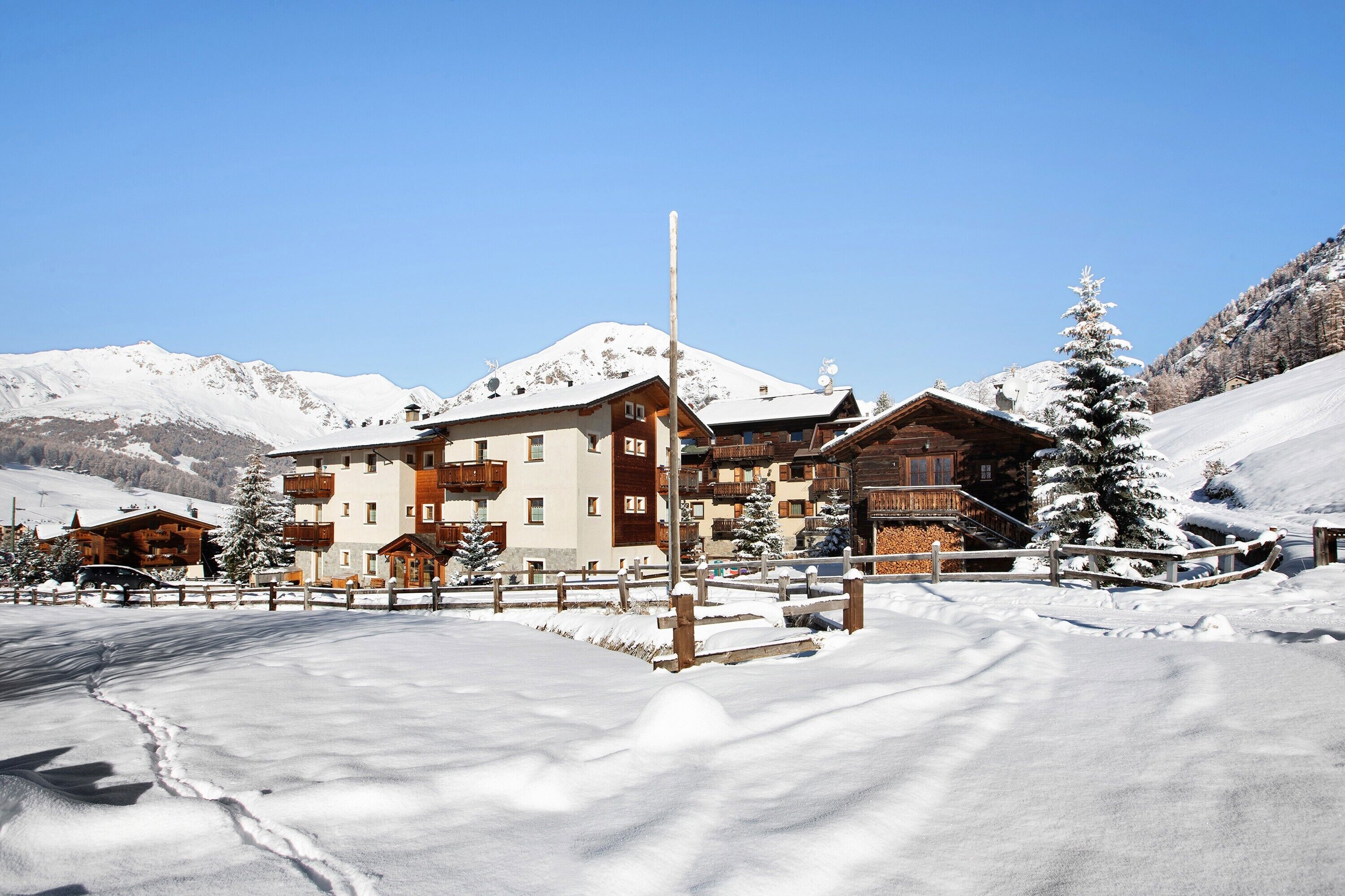 A snow-covered mountain resort with wooden buildings and a clear sky.