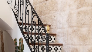 A staircase with ornate black railings and patterned tiles, a potted cactus, and a rustic chair. - Holiday Home 'Casa Roques 16' with Private Terrace, Wi-Fi and Air Conditioning (Xabia)