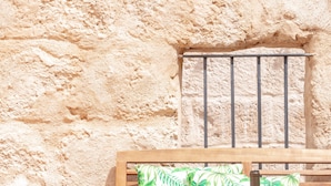 A wooden bench with a cactus, a bottle, and a bowl of snacks against a textured wall. - Holiday Home 'Casa Roques 16' with Private Terrace, Wi-Fi and Air Conditioning (Xabia)