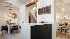 A modern kitchen with a white countertop, black cabinets, and a dining area with a white table and black chairs. - Holiday Home 'Casa Roques 16' with Private Terrace, Wi-Fi and Air Conditioning (Xabia)