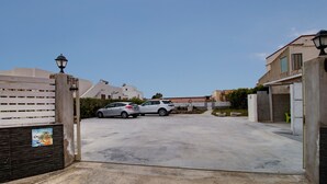 A gated residential area with two parked cars, a clear sky, and modern buildings. - Apartment 'Brezza Marina In Oasi Del Mare' with Sea View and Wi-Fi (Granelli)