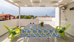 Una terraza techada con mesa, sillas y vistas al mar.
