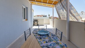A balcony with a patterned tablecloth, a blue bowl, and a chair. - Apartment 'Corallo In Oasi Del Mare' with Sea View and Wi-Fi (Granelli)