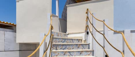 A staircase with white railings and yellow ropes, leading to a building with a tiled wall.