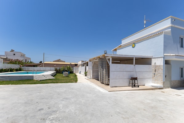 A modern house with a swimming pool, a covered patio, and a small garden.