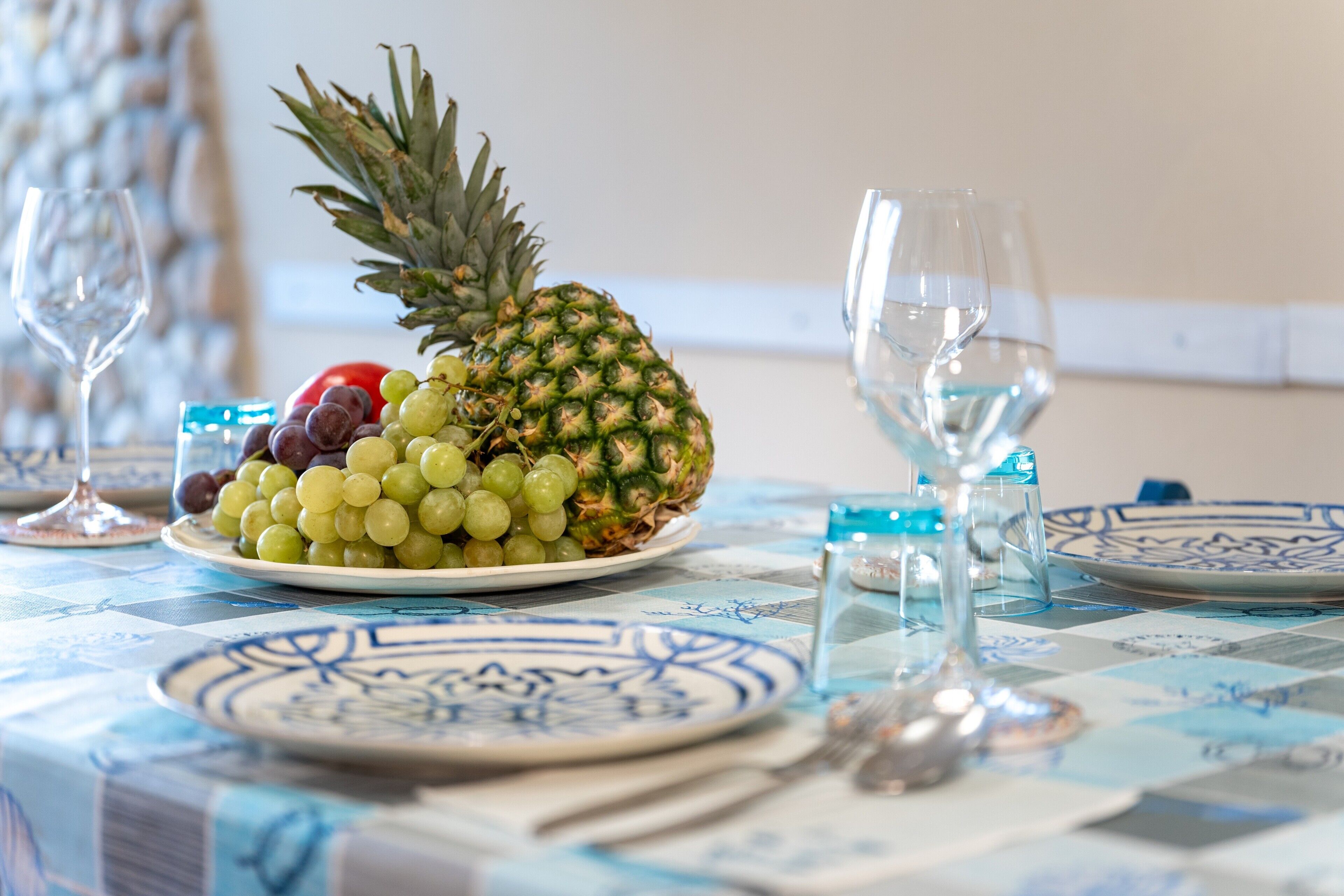 Uma mesa posta com abacaxi, uvas e um copo de água.