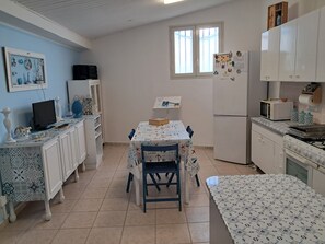 A kitchen with a dining table, chairs, a refrigerator, a microwave, and a stove. - Holiday Home 'Loft Le Palme' with Private Terrace, Wi-Fi and Air Conditioning (Portopalo di Capo Passero)
