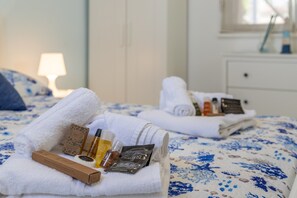 Un lit bien fait, avec des serviettes pliées, une bouteille de lotion et une boîte de produits de toilette.