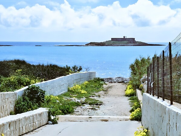 A pathway leading to a coastal area with a view of the sea and a distant structure. - Holiday Home 'Loft Le Palme' with Private Terrace, Wi-Fi and Air Conditioning (Portopalo di Capo Passero)