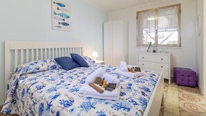 A bedroom with a bed, a dresser, a window, and a wall with a fish painting. - Holiday Home 'Loft Le Palme' with Private Terrace, Wi-Fi and Air Conditioning (Portopalo di Capo Passero)