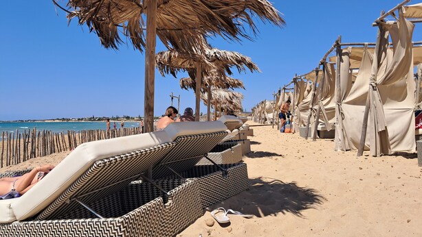 A beach with sun loungers, umbrellas, and beach huts. - Holiday Home 'Loft Le Palme' with Private Terrace, Wi-Fi and Air Conditioning (Portopalo di Capo Passero)