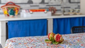 Une table recouverte d’une nappe à motifs, une grenade et un panier.