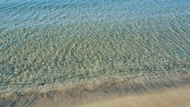 Une plage propre, avec une eau peu profonde et un rivage sablonneux.