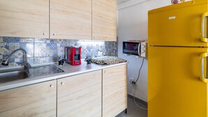 Une cuisine avec des meubles de rangement en bois, un évier, une machine à café rouge, un four à micro-ondes et un réfrigérateur jaune.