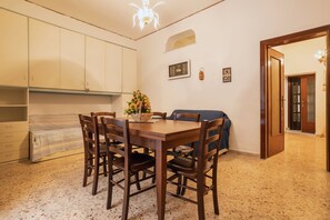 Uma área de refeições com mesa e cadeiras de madeira, uma planta em vaso e um candelabro.