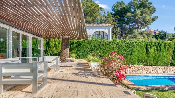 A wooden deck with outdoor seating, a swimming pool, and a building with large windows. - Villa 'Traviata ' with Sea View, Private Pool, Wi-Fi and Air Conditioning (Benissa(Alicante))