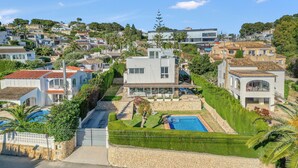 A residential area with a modern house featuring a swimming pool, a well-maintained garden, and a view of the surrounding neighborhood. - Villa 'Traviata ' with Sea View, Private Pool, Wi-Fi and Air Conditioning (Benissa(Alicante))