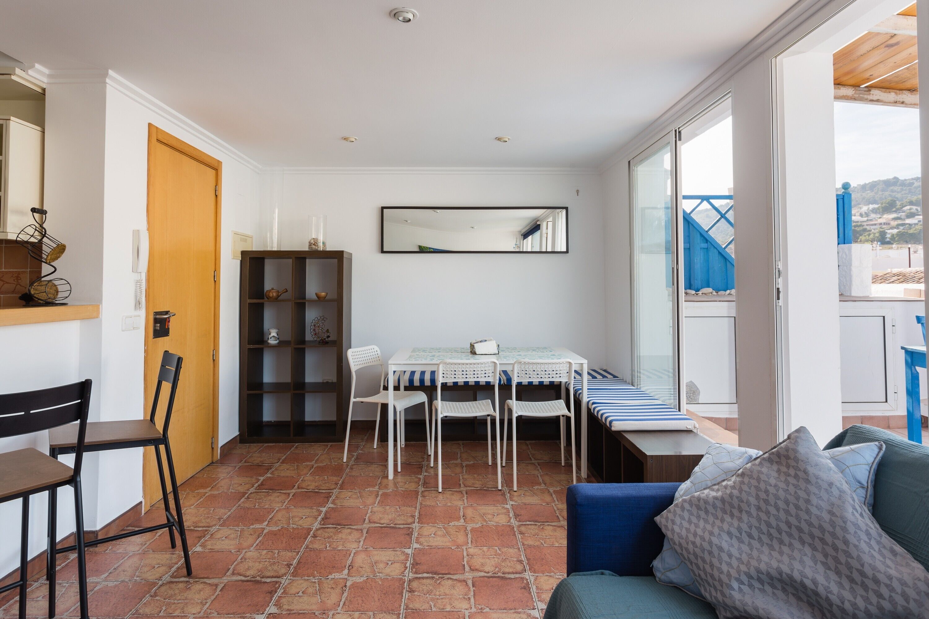Una habitación con una mesa de comedor, sillas, un sofá, una estantería y un ventanal grande.