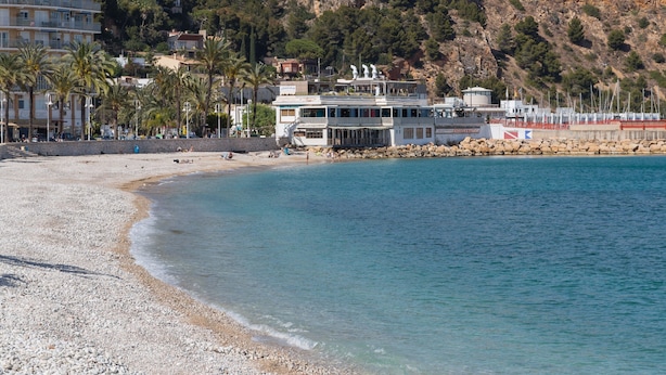 Ein Hotel an der Küste mit Blick auf den Strand, einem Pool und einem Bergpanorama.