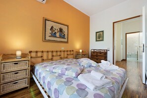 Ein Schlafzimmer mit Bett, Nachttischen, einer Lampe, einem Korb und einem Bild an der Wand.