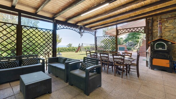Un patio al aire libre con mobiliario de mimbre, una chimenea de piedra y vistas al exterior.