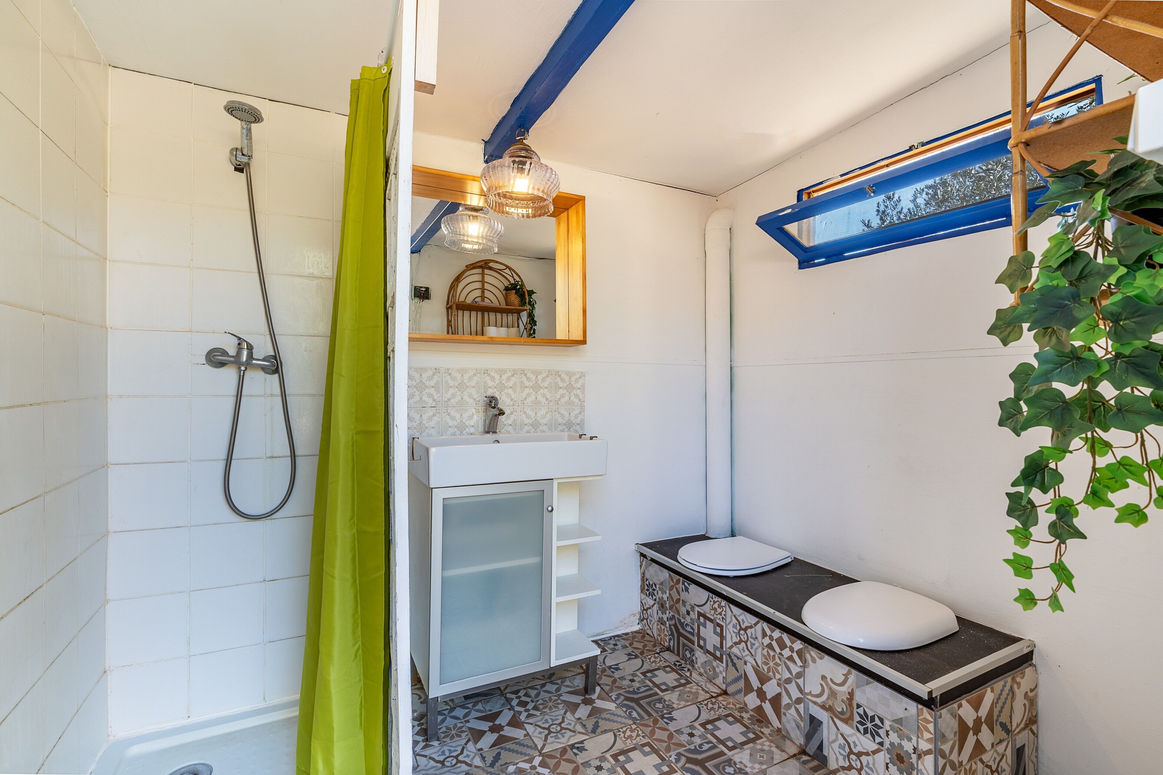 Ein Badezimmer mit Dusche, Waschbecken, Spiegel und Fenster.