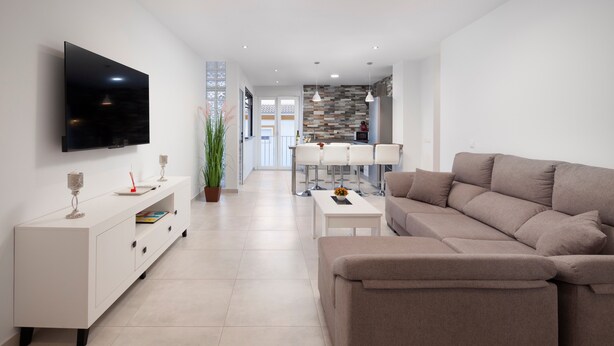 Un salon moderne avec un téléviseur à écran plat, un canapé, une table basse et un coin repas à l’arrière-plan.