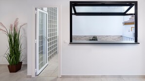 Un intérieur moderne avec une porte vitrée donnant sur un balcon, une plante en pot et une fenêtre fixée au mur.