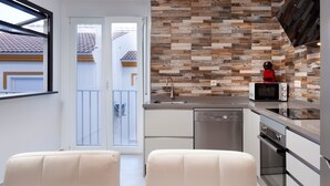 Une cuisine moderne dotée d’un revêtement mural original imitant le grain du bois, d’appareils électroménagers en acier inoxydable et d’une porte-fenêtre coulissante donnant sur un balcon.