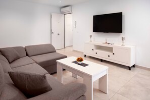 A modern living room with a sofa, a coffee table, a TV, and a white cabinet.