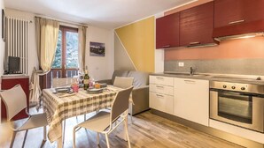 Eine kleine Küche mit Essbereich, einem Fernseher und einem Fenster mit Vorhängen.