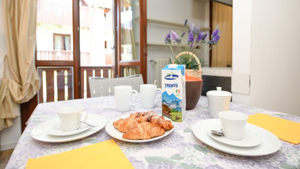 Ein Frühstückstisch mit Croissants, Kaffeetassen und einer Milchpackung.