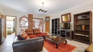 A living room with a sofa, coffee table, TV, bookshelf, and a fireplace. - Holiday Home 'My Friendly House' with Sea View, Wi-Fi and Air Conditioning (Lagos)