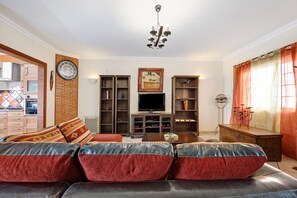A living room with a sofa, television, and shelves.