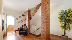 A staircase with wooden steps and a brick column, a black leather sofa, and a potted plant with yellow flowers. - Holiday Home 'My Friendly House' with Sea View, Wi-Fi and Air Conditioning (Lagos)