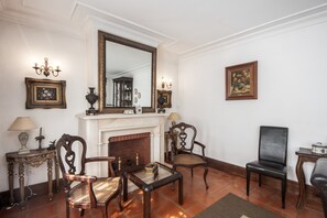 A room with a fireplace, two wooden chairs, a table, a mirror, and wall-mounted lamps. - Casa do Terreiro with private pool, private terrace, and Wi-Fi (Barqueiros)