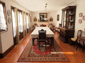 A dining room with a long table, chairs, a fireplace, and a cabinet with decorative plates.