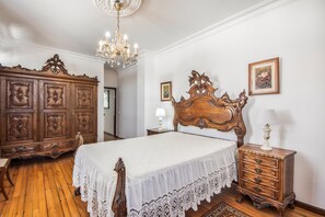 A bedroom with a large wooden bed, a wooden dresser, a nightstand, and a chandelier. - Casa do Terreiro with private pool, private terrace, and Wi-Fi (Barqueiros)