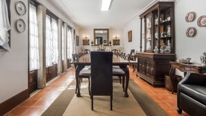 Een eetkamer met een lange tafel, stoelen, een kast en een spiegel.