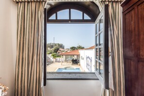 Un umbral abierto que da a un patio con piscina, techo de tejas y vistas a una zona residencial.