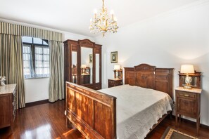 A classic bedroom with a wooden bed, a chandelier, a dresser, and a mirror. - Casa do Terreiro with private pool, private terrace, and Wi-Fi (Barqueiros)