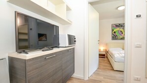 A compact room with a kitchenette, a bed, and a painting on the wall. - Apartment 'Rosa delle Dolomiti Bilocale2' with Mountain View and Wi-Fi (Carisolo)