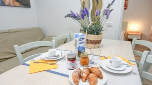 A dining table with croissants, a jar of jam, a carton of milk, and a basket of flowers. - Apartment 'Rosa delle Dolomiti Bilocale2' with Mountain View and Wi-Fi (Carisolo)