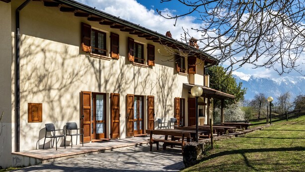 A building with a terrace, outdoor seating, and a view of mountains.