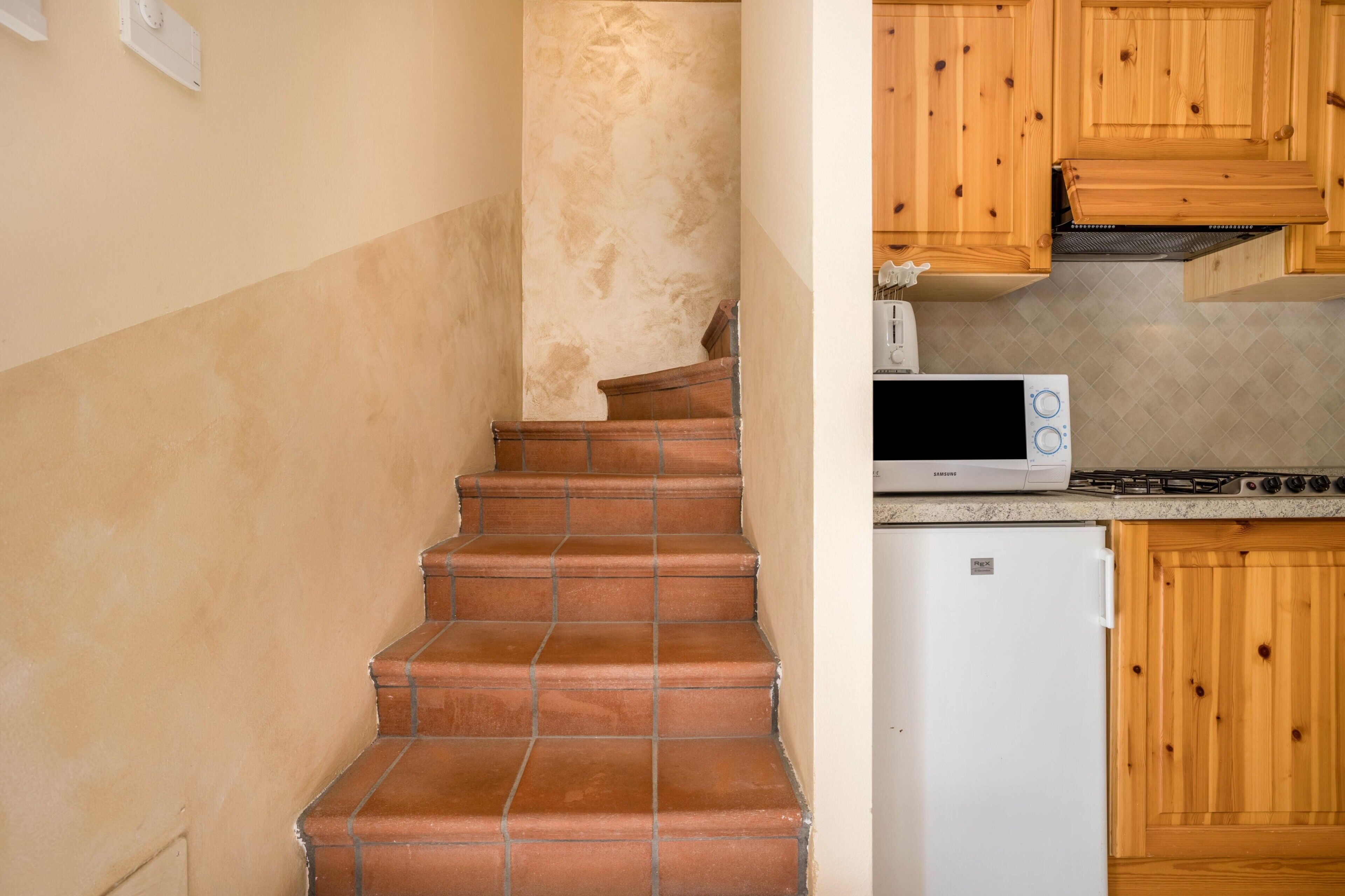 A kitchen with wooden cabinets, a microwave, a stove, and a refrigerator.