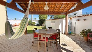 A covered patio with a round table and chairs, a hammock, and a hanging light fixture. - Holiday Home 'Moinho De Paradela' with Private Pool, Private Terrace and Wi-Fi (Paradela)