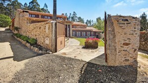 A stone building with a tiled roof, a gated entrance, and a pathway leading to a flower bed. - Holiday Home 'Azenha Da Lagoa Negra' with Lake View, Private Pool and Wi-Fi (Barqueiros)
