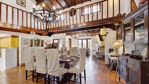 A dining area with a wooden table and chairs, a chandelier, and a cabinet with glass doors. - Holiday Home 'Azenha Da Lagoa Negra' with Lake View, Private Pool and Wi-Fi (Barqueiros)