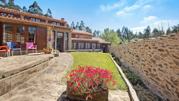 A stone building with a tiled roof, a stone wall, and a grassy area with red flowers. - Holiday Home 'Azenha Da Lagoa Negra' with Lake View, Private Pool and Wi-Fi (Barqueiros)