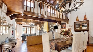 A dining area with a wooden table, chairs, a chandelier, and a stone wall. - Holiday Home 'Azenha Da Lagoa Negra' with Lake View, Private Pool and Wi-Fi (Barqueiros)